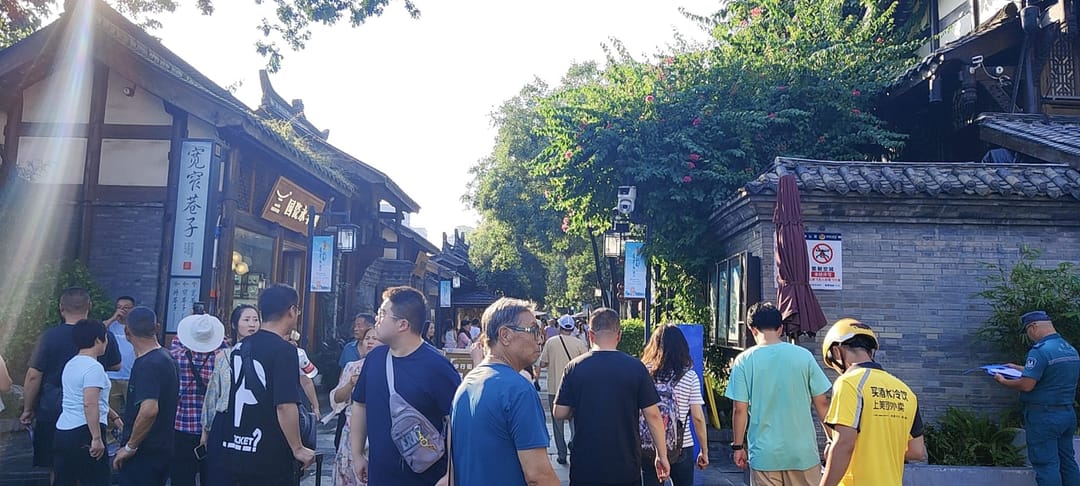 Una multitud recorre un callejón estrecho de casas de patio de ladrillo gris con fachadas de madera en Kuanzhai Xiangzi