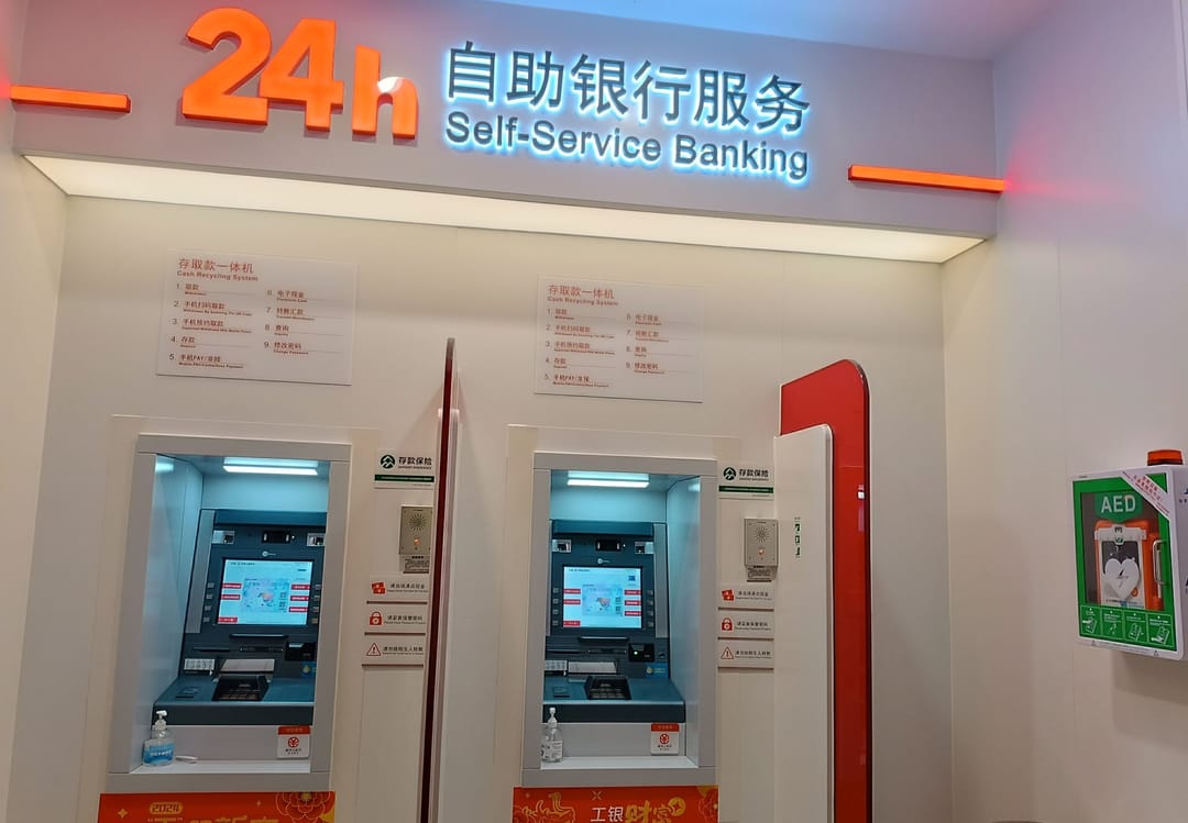 Zwei Geldautomaten der ICBC unter einem beleuchteten Schild „24h Self-Service Banking“ in Shenzhen