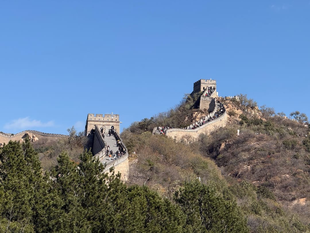Visitors climbing the Great Wall at Badaling in a long line between two watchtowers, under a clear autumn sky