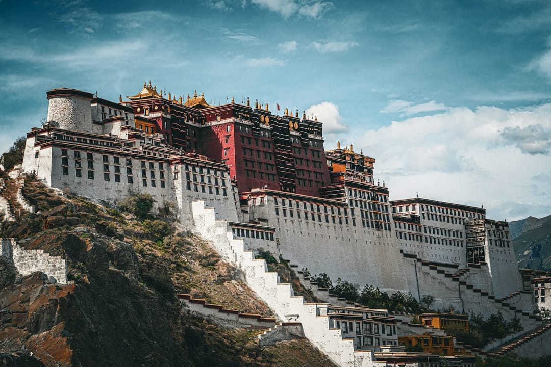 Il palazzo del Potala a Lhasa, bianco e rosso, sulla collina sotto un cielo con nuvole