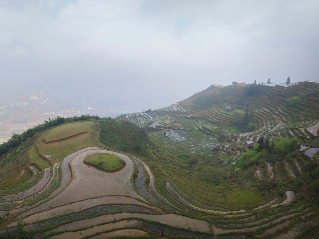 Teils geflutete Reisterrassen an einem Hang in Yuanyang in Yunnan, im Dunst