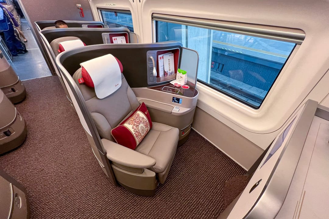 A business-class seat on a Chinese high-speed train, a single grey reclining seat in its own shell beside the window