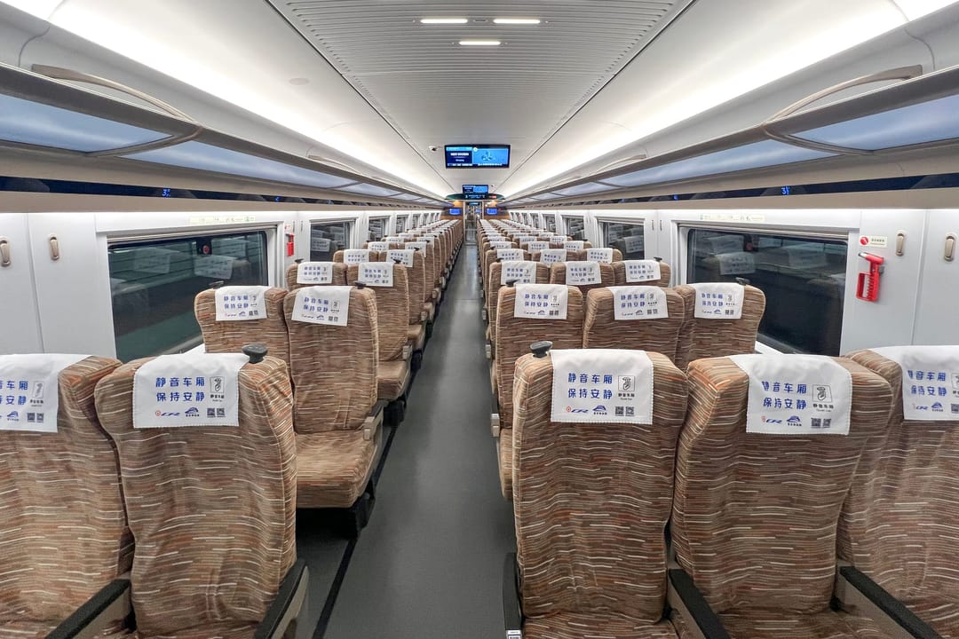 The empty second-class carriage of a Chinese high-speed train, three seats on the left and two on the right, luggage racks above
