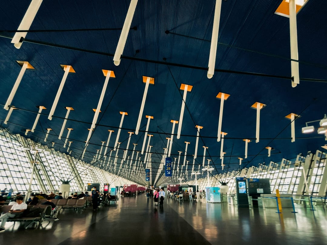 Sala partenze del Terminal 1 dell'aeroporto di Shanghai Pudong con viaggiatori sotto la copertura curva