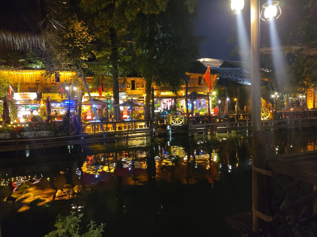 Locali illuminati lungo un canale di Wuzhen di sera, con le luci che si riflettono nell’acqua