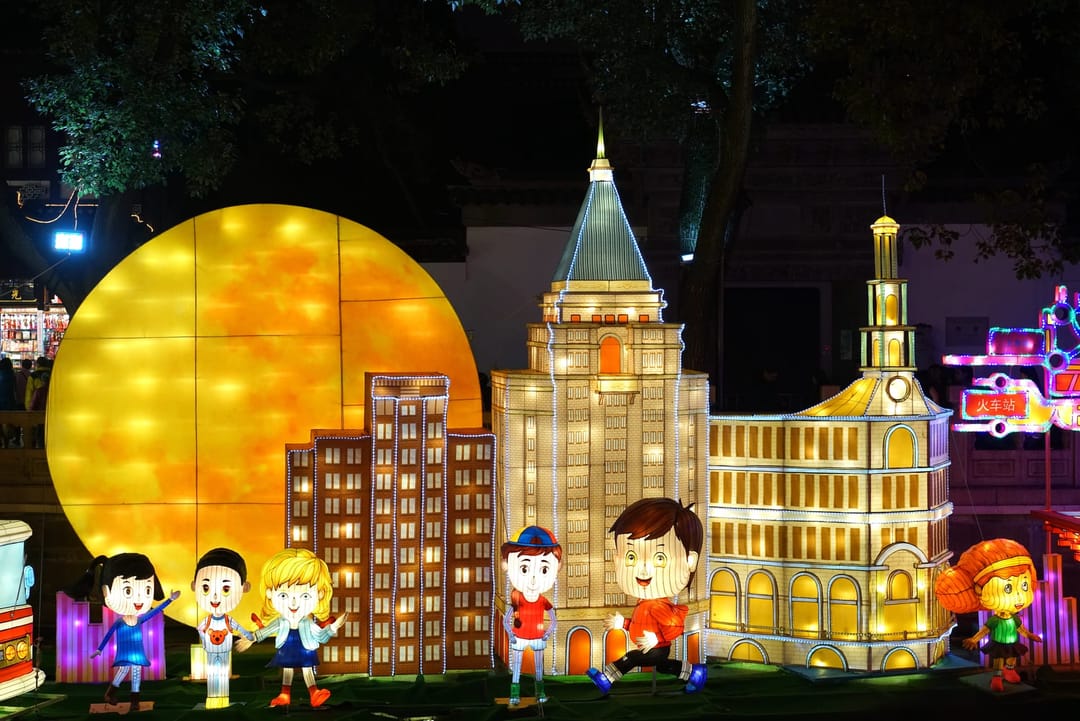 Lantern models of Shanghai landmarks and cartoon children glowing at night at the Yuyuan Lantern Festival