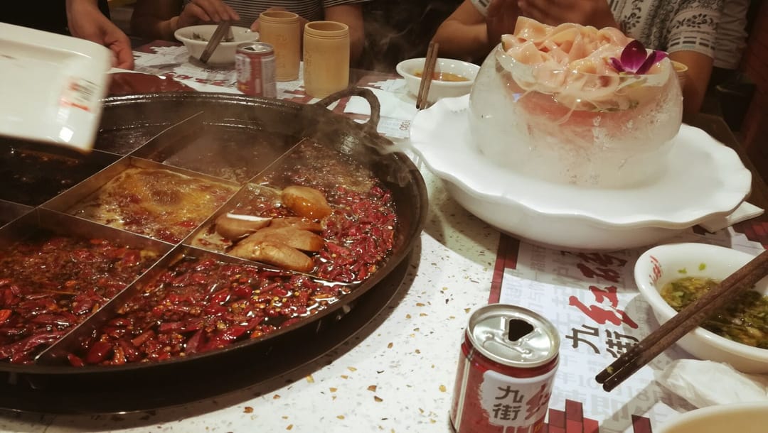 Un hotpot de Chongqing dividido en una cuadrícula de casillas, con caldo rojo de chile lleno de pimienta y un cuenco de hielo