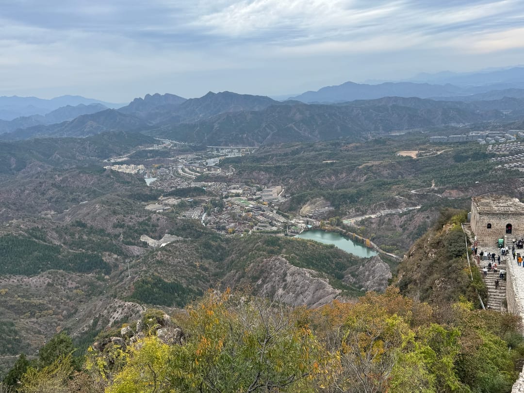 View from the Simatai section of the Great Wall over a valley with a reservoir and the rooftops of Gubei Water Town