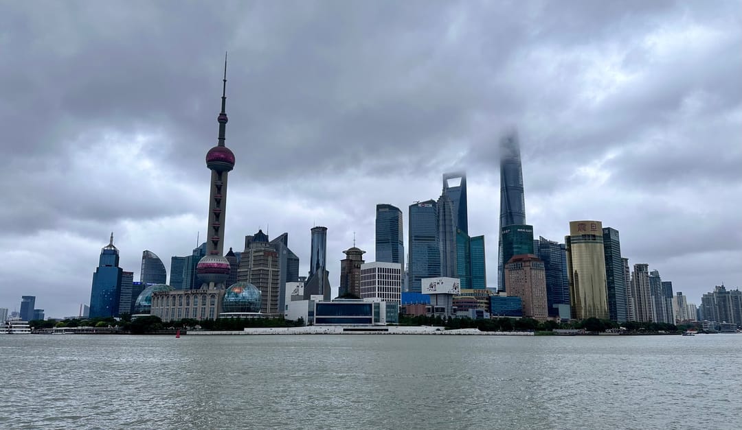 Die Skyline von Pudong unter grauem Himmel, vom Bund aus gesehen, mit dem Oriental Pearl Tower links und dem Shanghai Tower in den Wolken