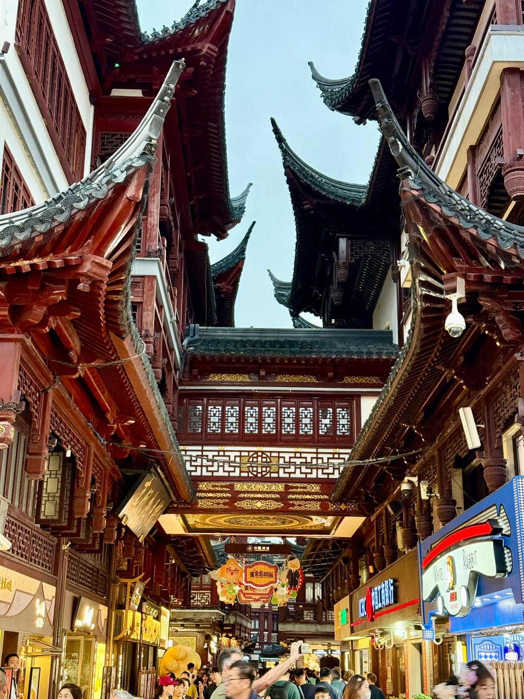Edifici in stile tradizionale con tetti ricurvi, travi rosse e finestre a grata nelle strade del bazar di Yuyuan