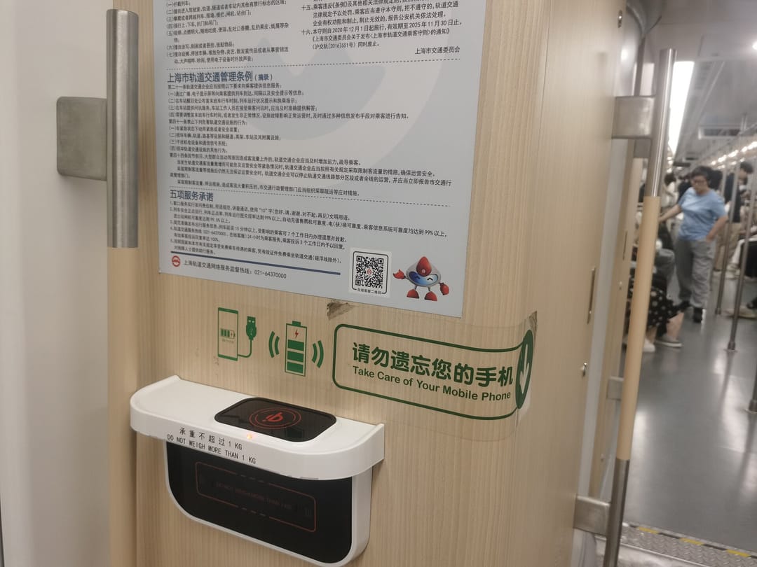 Base de carga inalámbrica en la pared de un vagón del metro de Shanghái, con un cartel que pide cuidar el móvil